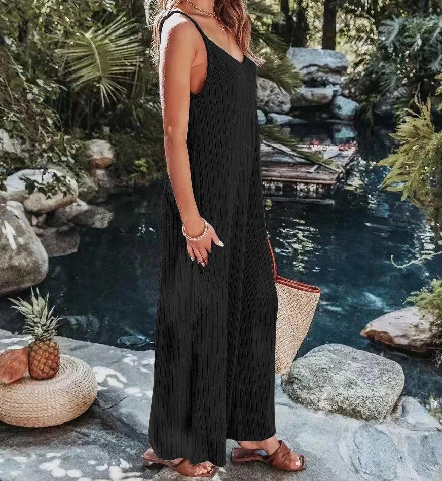 Black ribbed sleeveless jumpsuit for women, stylish summer outfit by poolside with woven bag and sandals