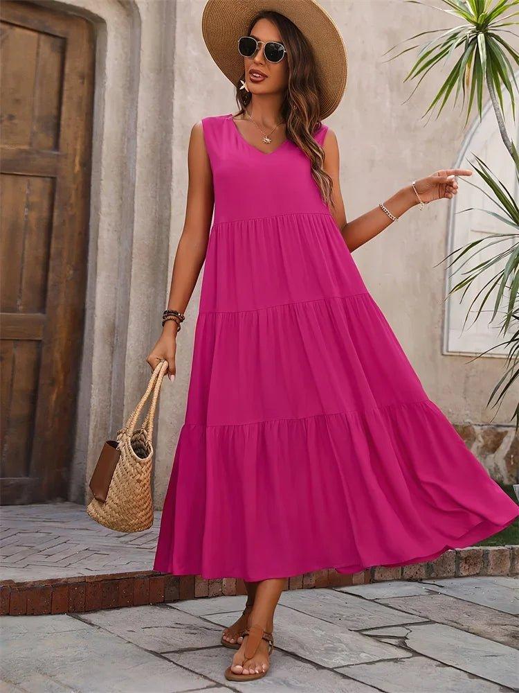Woman in vibrant pink tiered maxi dress, straw hat, and woven bag for summer fashion