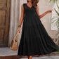 Woman in black tiered maxi dress with straw hat and woven bag, summer fashion outfit