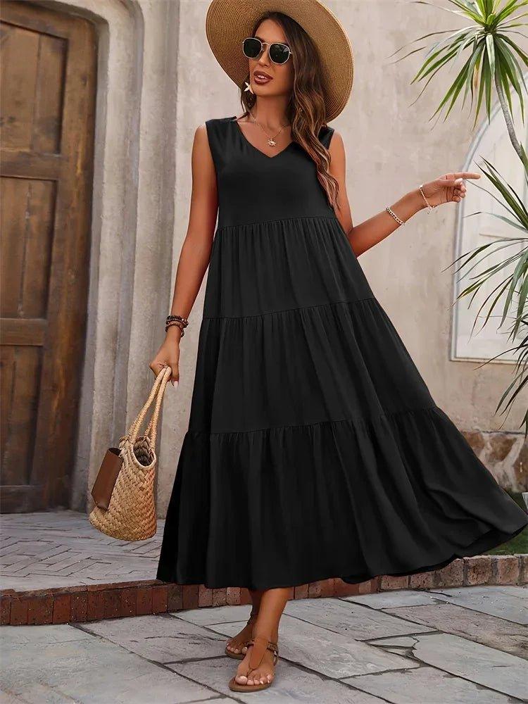 Woman in black tiered maxi dress with straw hat and woven bag, summer fashion outfit