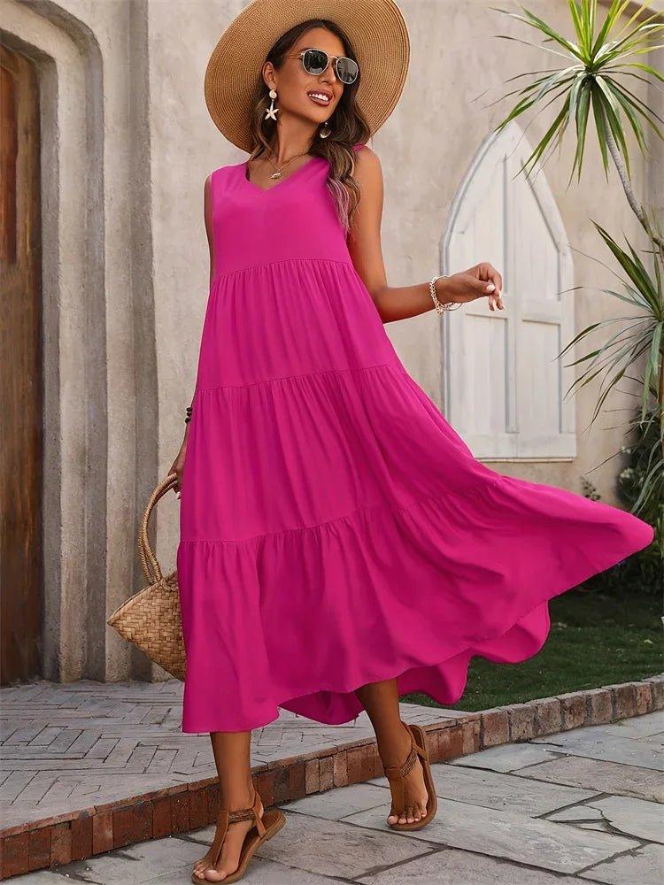 Woman in vibrant pink tiered maxi dress, straw hat, and sandals for summer fashion