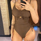 Woman in olive green one-piece swimsuit with ruched front and side ties, taking mirror selfie