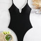 Black one-piece swimsuit with white trim, styled with straw bag and tulips for beach fashion