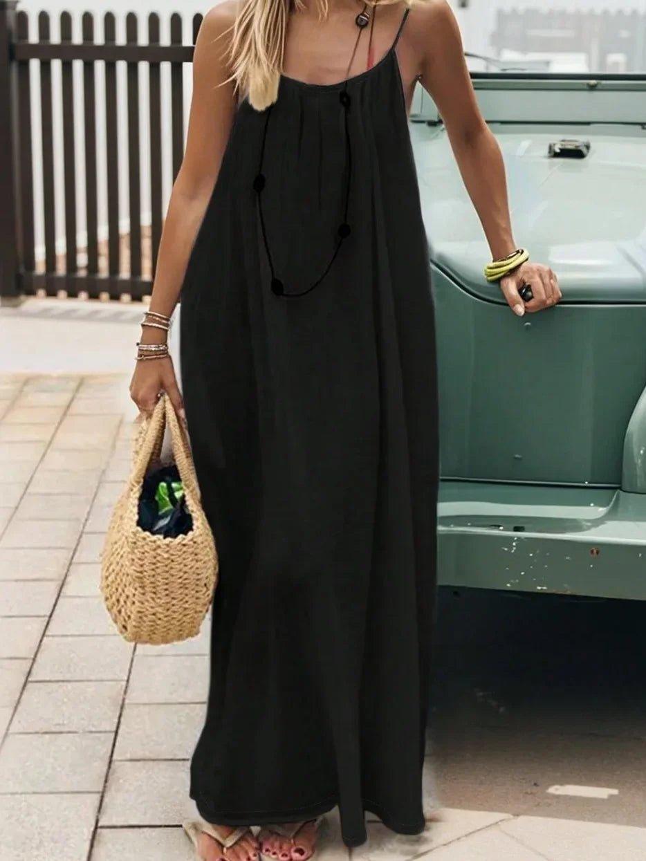 Woman in black spaghetti strap maxi dress with woven bag, summer fashion outfit