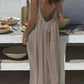 Woman in backless beige maxi dress at outdoor table with bowls and fruit, summer fashion