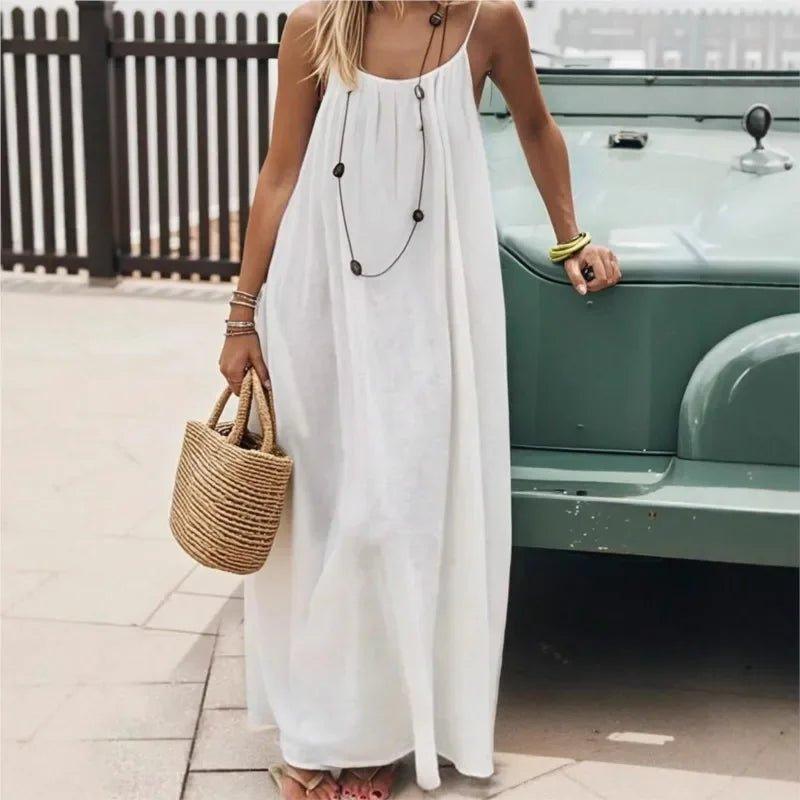 Woman in white maxi dress with straw bag and layered necklace