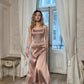 Elegant woman in blush satin strapless midi dress, standing by arched window in vintage room