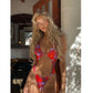 Woman in red and blue tie-dye one-piece swimsuit with cutouts and rhinestone details, indoor setting