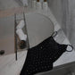 Black rhinestone-embellished camisole on marble bathroom counter beside bathtub with towel rack