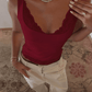 Woman wearing burgundy lace trim tank top with white pants, diamond necklace, and ring for stylish fashion look