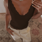 Woman in black scalloped tank top with white pants, diamond necklace, and rings — stylish fashion outfit