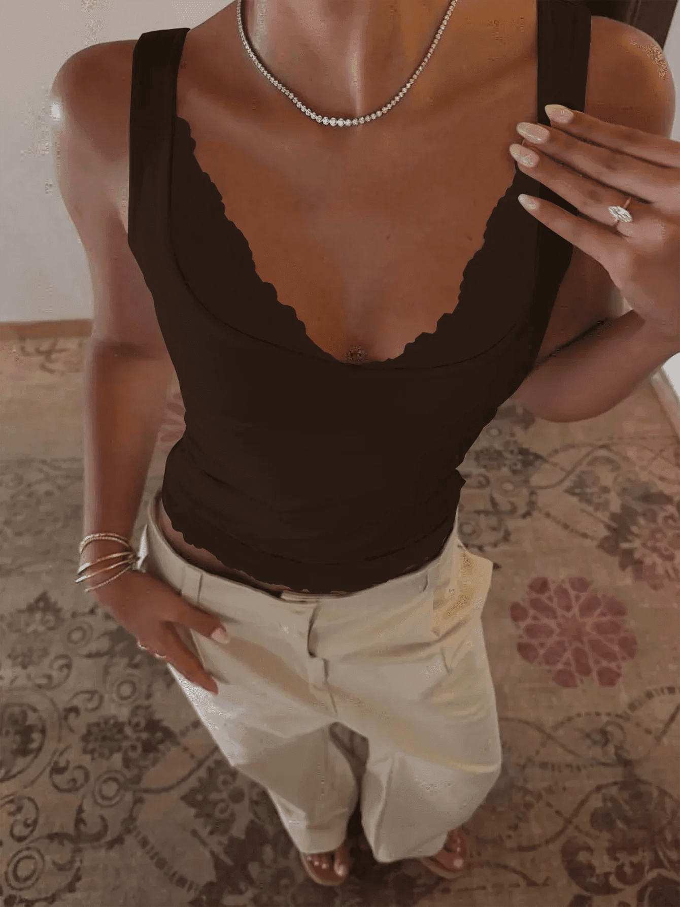 Woman in black scalloped tank top with white pants, diamond necklace, and rings — stylish fashion outfit