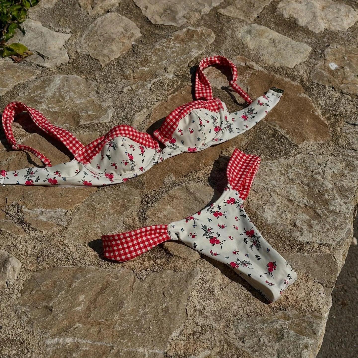Floral print bikini with red gingham trim, laid on stone surface