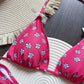 Pink floral bikini top with white daisy print, paired with straw hat on woven mat