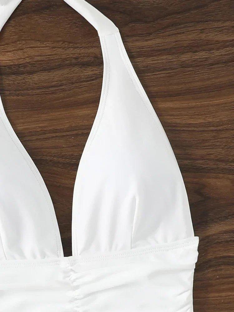 White halter neck swimsuit top with ruched detail on wooden background