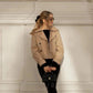 Woman in beige trench coat with black top, pants, and quilted handbag, stylish street fashion look