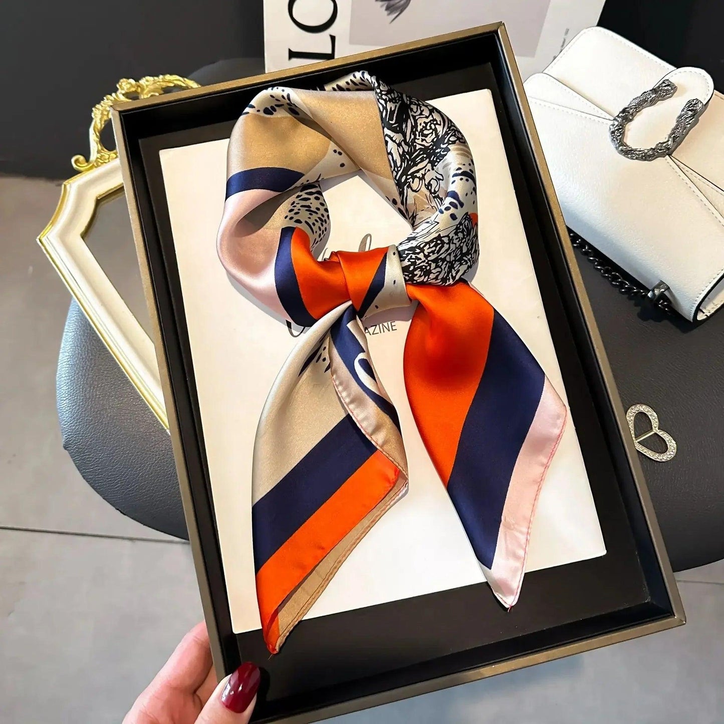 Elegant silk scarf with floral and stripe print in orange, navy, and beige, styled in gift box for women's fashion.