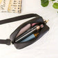 Black women's crossbody bag with gold zipper, holding phone, lipstick, and essentials on white background