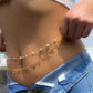 Gold body chain with pearls and butterfly charms, worn as waist jewelry with denim shorts