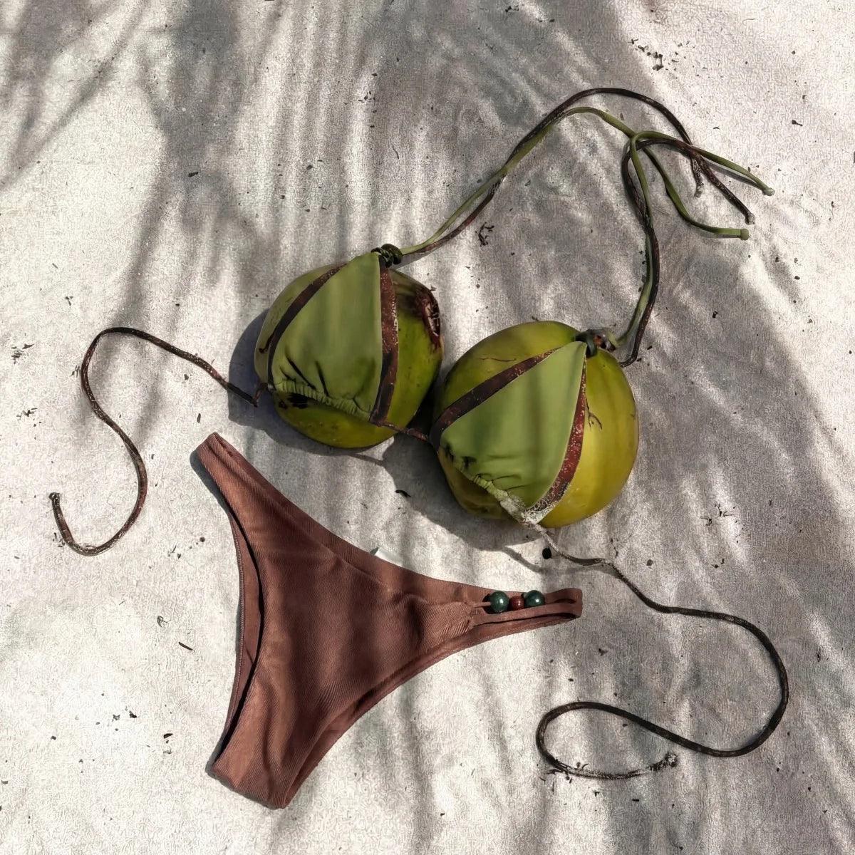 Coconut shell bikini top with brown string bottoms on sandy beach, tropical beachwear fashion