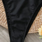 Black high-cut bikini bottom on woven mat with yellow flower, women's swimwear fashion
