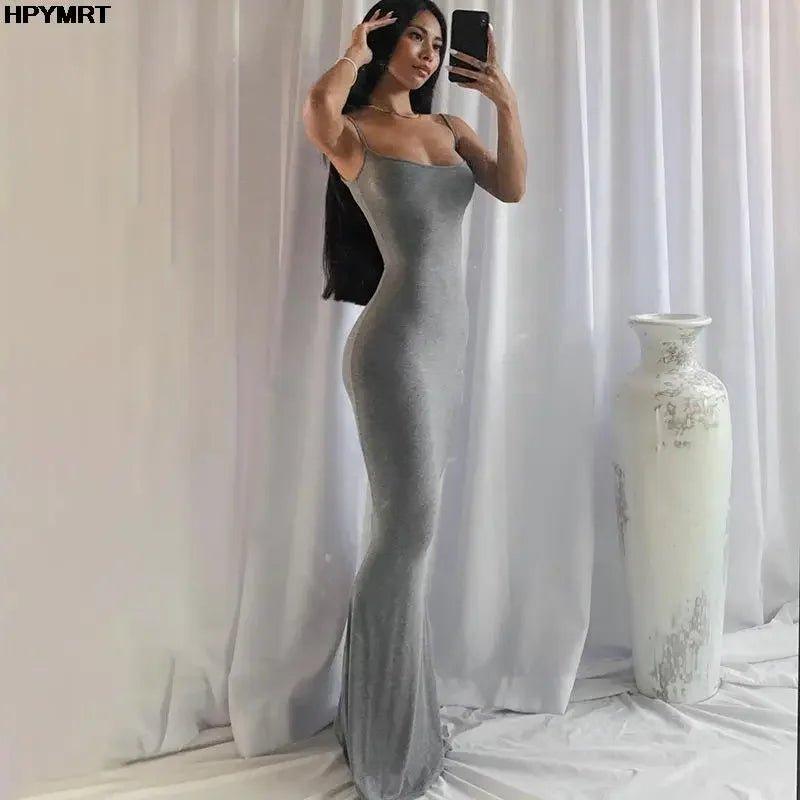 Woman in elegant gray velvet maxi dress, taking mirror selfie with white vase backdrop, fashion style