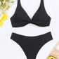 Black ribbed bikini set with twist front top and high-cut bottoms, styled with yellow flowers and avocado