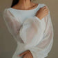 Woman in elegant white off-shoulder blouse with sheer puff sleeves, fashion top