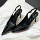 Black patent leather pointed-toe slingback heels with red soles, elegant women's fashion footwear