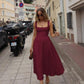 Woman in elegant burgundy midi dress walking city street, fashion style