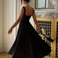 Woman in elegant black midi dress with open back, twirling in luxury interior