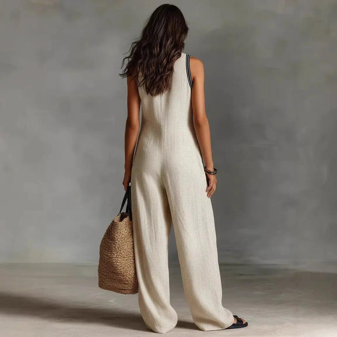 Woman in beige sleeveless wide-leg jumpsuit with straw bag, back view