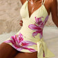 Woman in floral print yellow swimsuit with side tie, beach setting, fashion swimwear