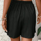 Black pleated high-waist women's shorts with elastic waistband, paired with white crop top for summer fashion