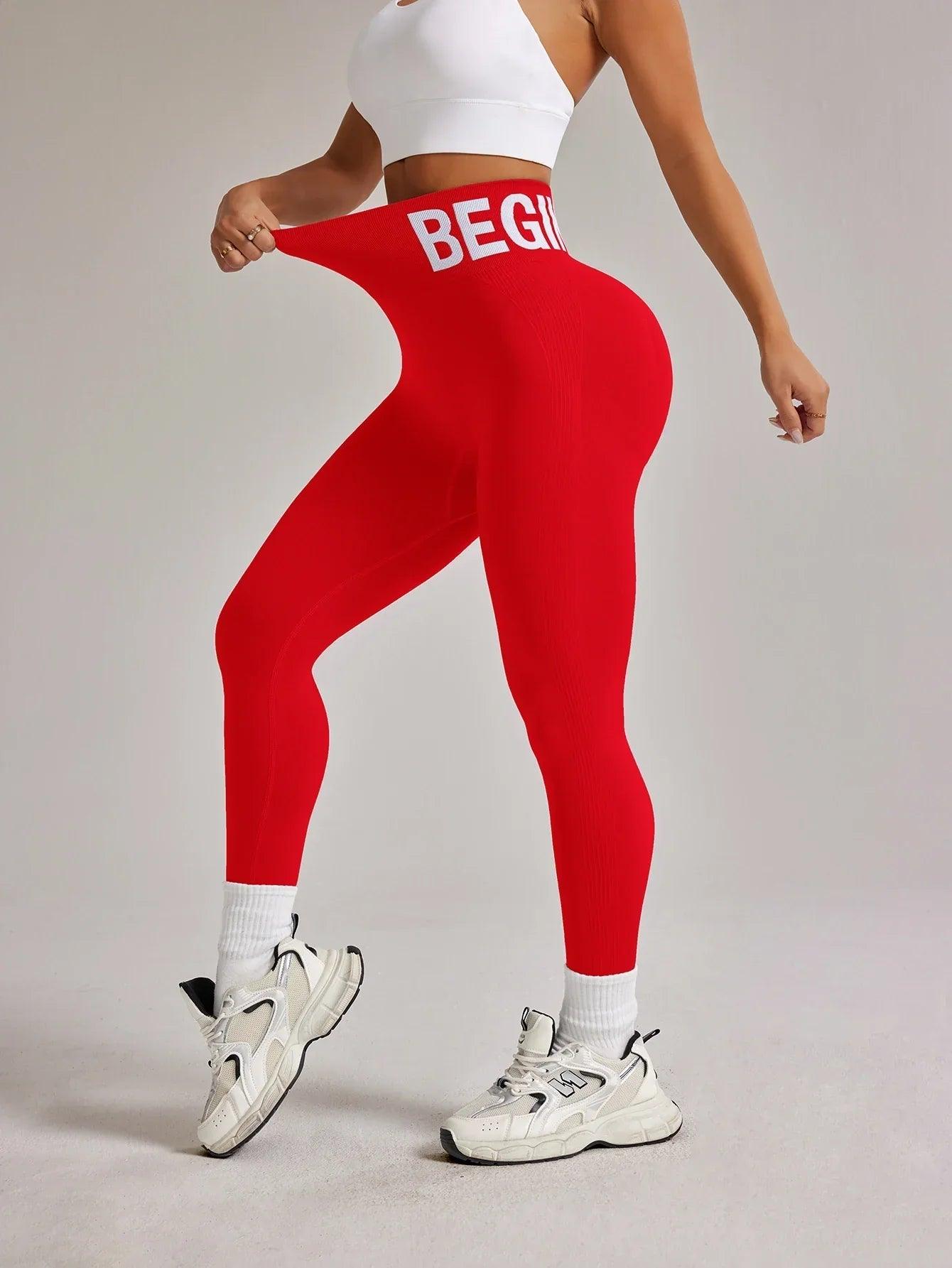 Red high-waist leggings with 'BEGIN' waistband, paired with white sports bra and sneakers for women's fitness fashion