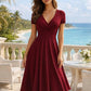 Woman in elegant burgundy wrap dress with V-neck, short sleeves, and flared skirt, perfect for beachside fashion.