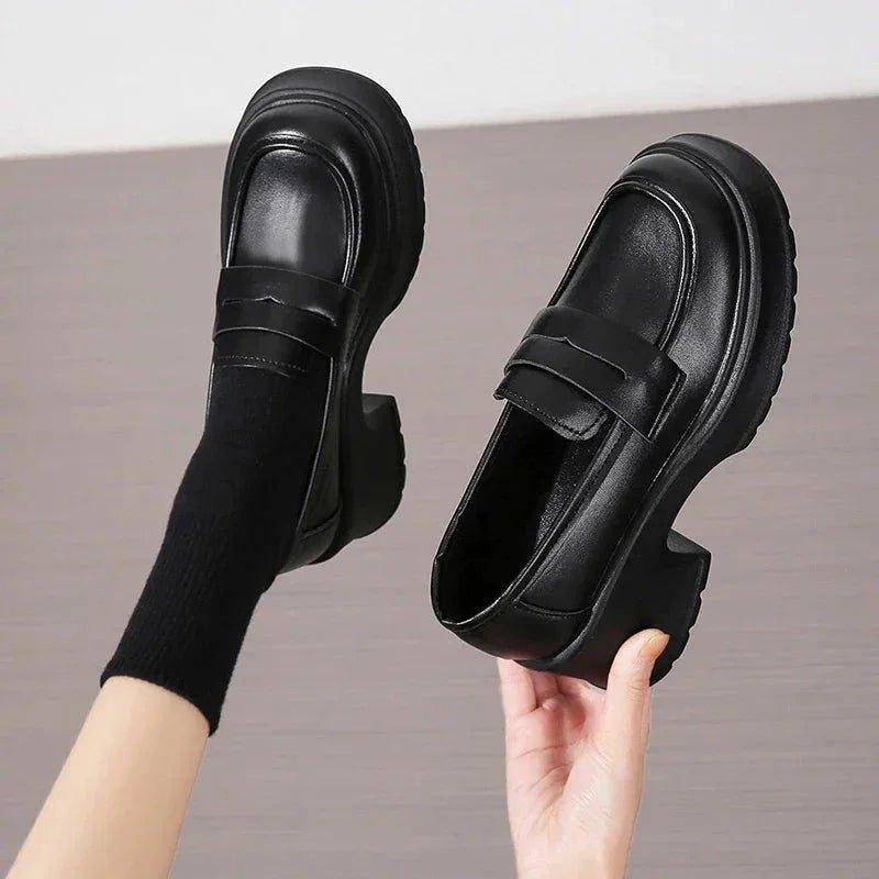 Black platform loafers with chunky heels, worn with black socks, perfect for women’s fashion