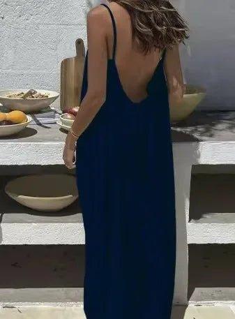 Woman in navy blue backless maxi dress at outdoor table, summer fashion style